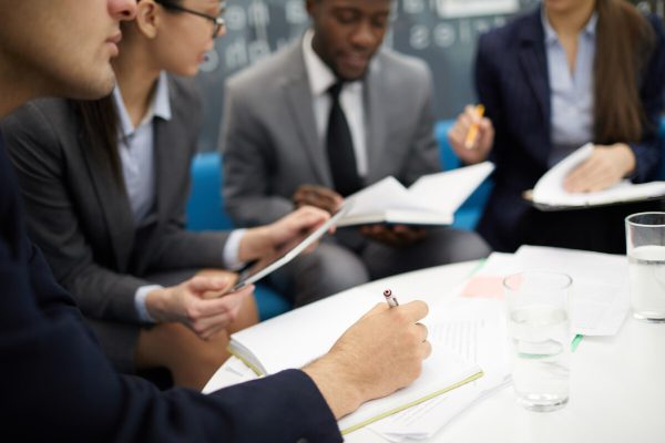 Cropped image of business people writing uring meeting in office, copy space